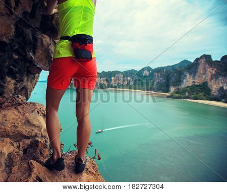 free solo woman rock climber climbing at seaside cliff