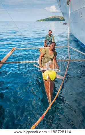 Hell-Ville Madagascar - December 19 2015: Malagasy vendors from their outrigger canoe offer fish and tropical fruits to ship passengers at Hell-Ville Nosy Be Island Madagascar.