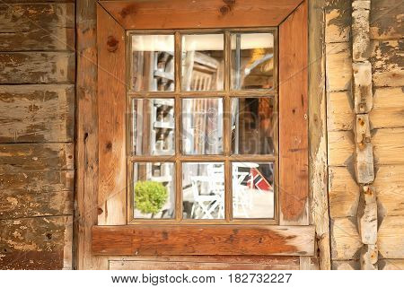 The window of the old wooden log house on the background of wooden walls