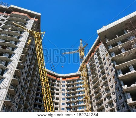 Two yellow crane building a multistory residential building blocks.