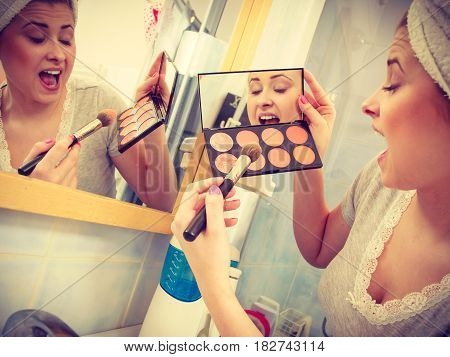 Woman In Bathroom Applying Contour Bronzer On Brush