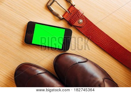 Closeup aerial view of white smart phone with green isolated screen on white wooden surface. Mockup. Copy space available.