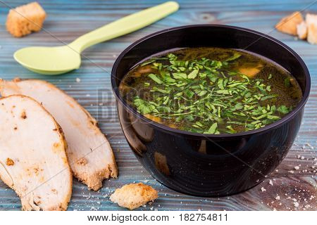 Chicken soup with toasts, a breast and greens, is served in plastic ware