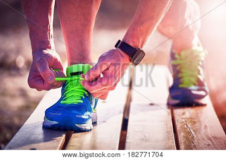 Athlete during training tying shoelaces on sneakers summer.