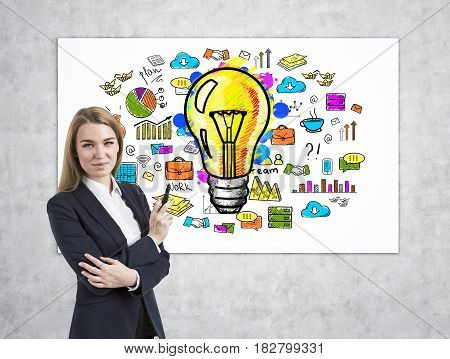 Portait of a cheerful woman business coach wearing a black suit and standing near a bright idea poster.