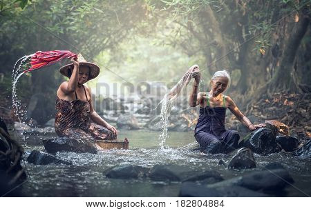 Asian old women washing clothes at the creek