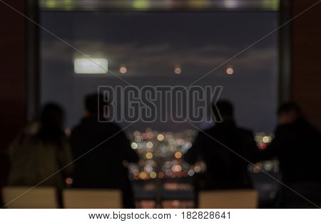 Blur toursits sitting on skyscraper observatory overlooking the city aerial view at night