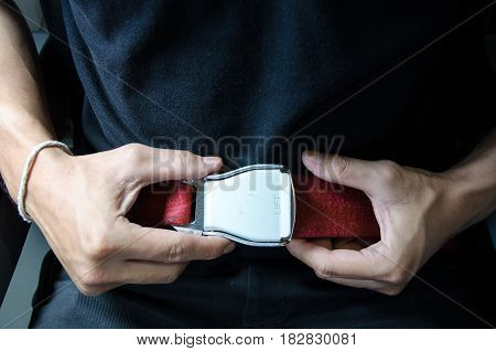 Hand of asian man unfasten seatbelt .