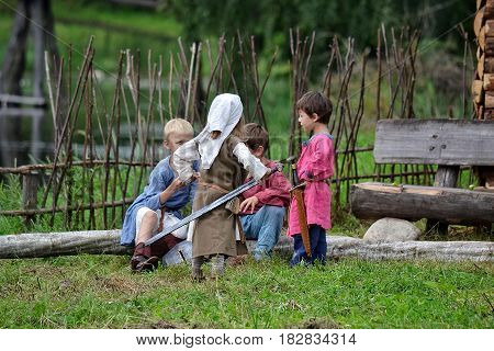 TERVETE LATVIA - AUGUST 13 2011: Historical Zemgalu days. Unknown children in ancient clothing with ancient weapons into groups standing and talking.