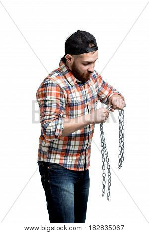 Redhead Bearded man wearing a baseball cap and shirt making streght against a chain. . Isolated on white.
