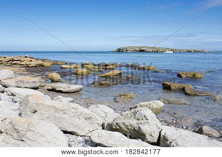 Rocky coastline at Moelfre Anglesey in North Wales with distant view of Moelfre Island (Ynys Moelfre)