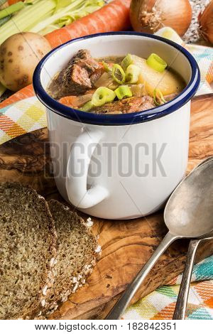 home made traditional irish lamb stew with potato carrot celery and spring onion in an white enamal cup