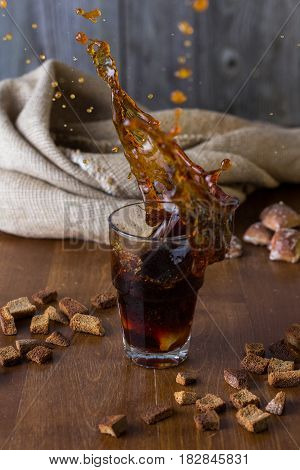 Traditional Russian drink kvass from bread rye malt sugar and water. Kvass in a glass on a dark wooden background. Splash