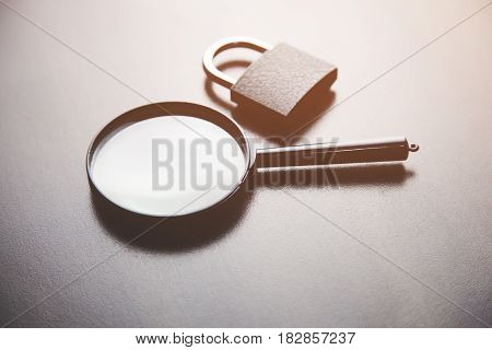 Padlock and magnifier on black table background