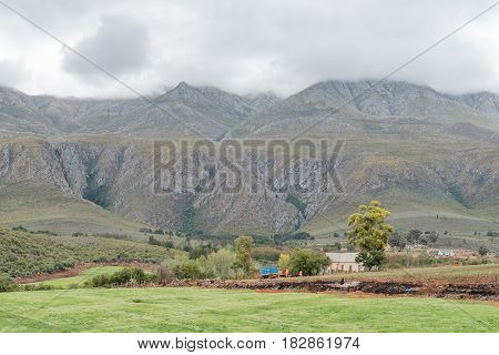 A farm landscape near Matjiesrivier with a vehicle visible on the Swartberg Pass in the back