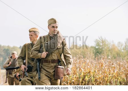 Dyatlovichi, Belarus - October 1, 2016: Reenactors Men Dressed As Russian Soviet Red Army Infantry Soldiers Of World War II Marching In Field With Weapon Machine-gun At Historical Reenactment