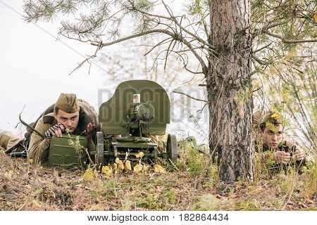 Dyatlovichi, Belarus - October 1, 2016: Reenactors Dressed As Russian Soviet Red Army Soldiers Of World War II Hidden Sitting With Maxim's Machine Gun Weapon In An Ambush In Autumn Forest
