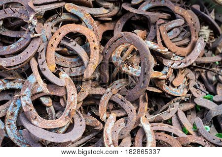 Heap of used and worn rusty Horseshoes outside blacksmith farriers shop or smithy