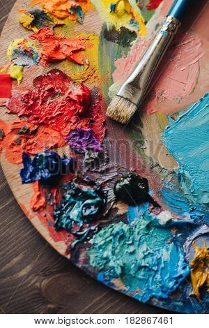color palette with fresh paint and brush on wood table