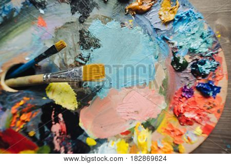 color palette with fresh paint and brush on wood table