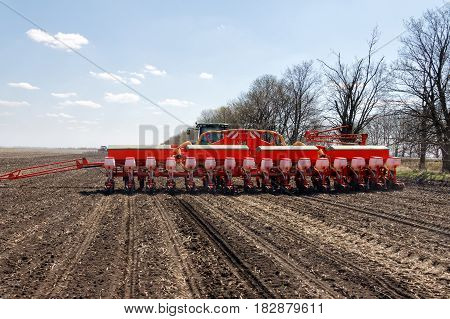 Tractor with trailed planter working in field in a sunny spring day