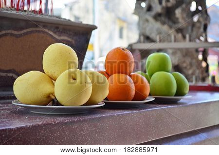 Yellow pears, oranges and green apples fruit offerings as a sacrifice at Chinese temple.