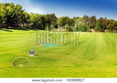 Flagsticks, markers and bunkers at the golf course in the midst of beautiful green wood