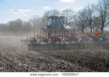 Kharkiv Ukraine - April 13 2017: Tractor with trailed planter working in field in a sunny spring day in Kharkiv Oblast Ukraine on April 13 2017