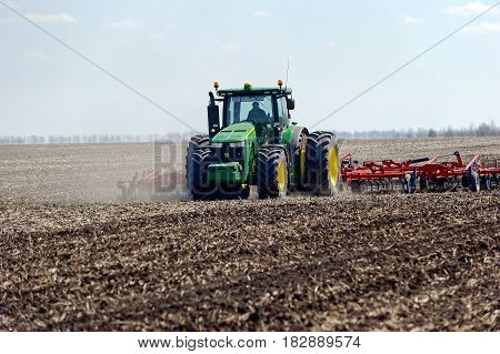 Kharkiv Ukraine - April 13 2017: Tractor with trailed planter working in field in a sunny spring day in Kharkiv Oblast Ukraine on April 13 2017