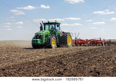 Kharkiv Ukraine - April 13 2017: Tractor with trailed planter working in field in a sunny spring day in Kharkiv Oblast Ukraine on April 13 2017