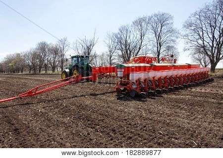 Kharkiv Ukraine - April 13 2017: Tractor with trailed planter working in field in a sunny spring day in Kharkiv Oblast Ukraine on April 13 2017