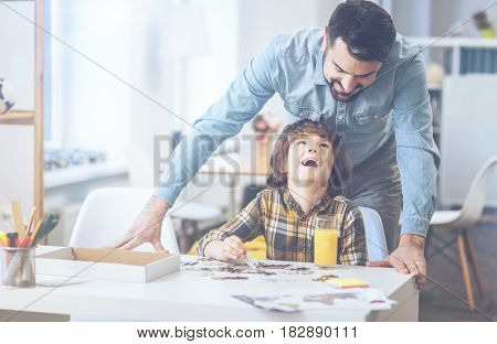 Daddy, you are the best. Cuttest little boy laughing at a joke heartily and looking at his father while playing in family circle