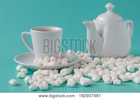 Pastel marshmallow in a white cup on a blue background. Sweet unhealthy food. Minimalism style