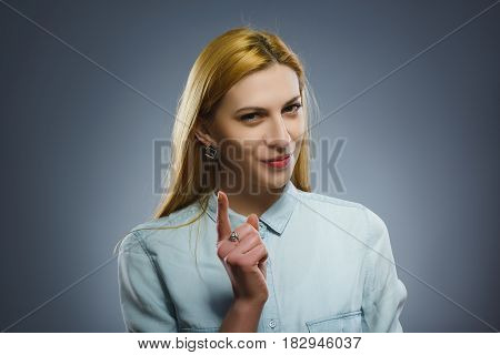 displeased and contemptuous girl with threatens finger isolated on gray background