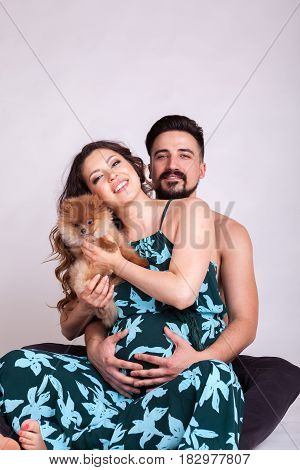 Happu pregnant woman with her husband and dog in studio photo. Wife and husband. Parenthood and expecting baby