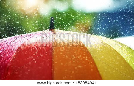 Rain drops falling onto umbella with rainbow colour- Rainy weather