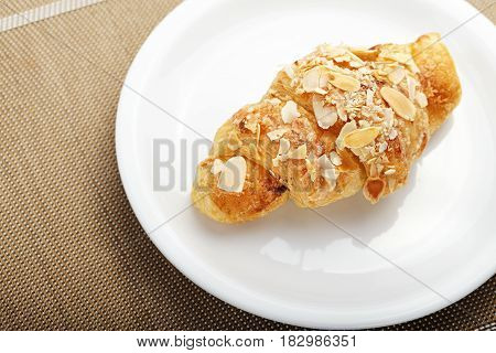 Traditional French breakfast croissant with almonds on a platel on a napkin