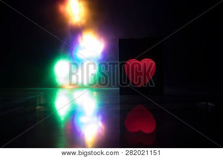 Blurred Neon Heart Icon On A Dark Background. Copy Space With Red Bright Colorful Heart On Black Bac