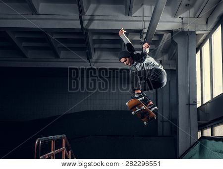 Skateboarder Jumping High On Mini Ramp At Skate Park Indoor.
