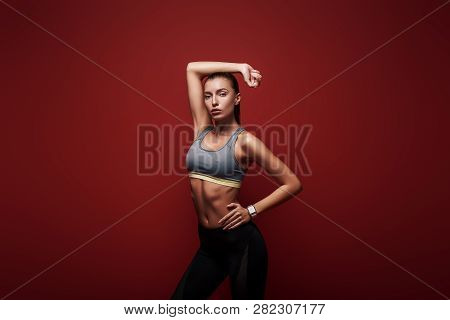 Power And Beauty. Sportswoman Standing Over Red Background, Looking Away