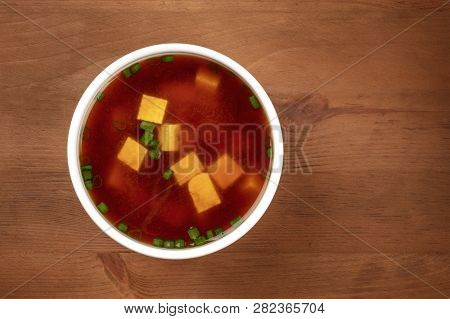 A Bowl Of Miso Soup With Tofu And Scallions, Shot From The Top On A Dark Rustic Background With Copy