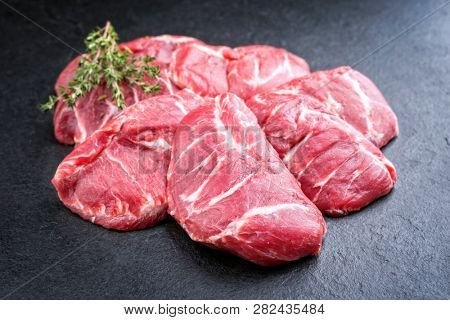 Traditional German raw pork cheeks with hers as closeup on a black board 