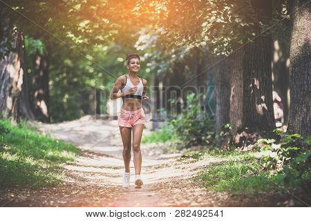 Young Lady Running. Woman Runner Running Through The Summer Park Road. Workout In A Park. Beautiful 