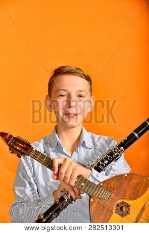 A Handsome Boy Holds A Clarinet And A Dombra In Two Hands.