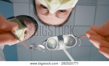 Pov Of Patient During Visit At Dentist. Two Doctors Are Doing Surgery In Clinic