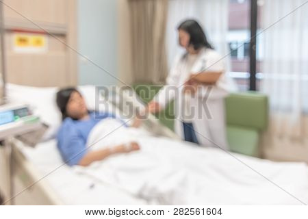 Doctor Visiting Patient On Hospital Bed, Medical Blurred Background With Blurry Interior White Room 