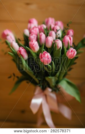 A Bouquet Of Pink Tulips In Womans Hands. Woden Background