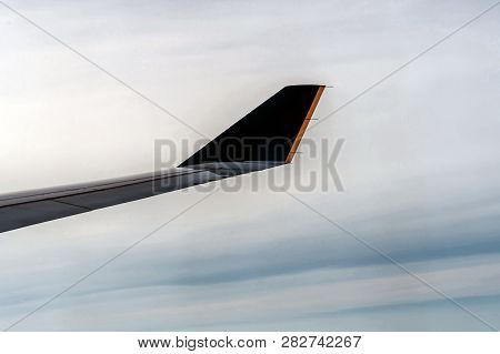 Commercial Aircraft Wingtip Silhouetted Against Soft White Cloud Bank In Flight.
