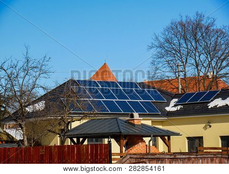 Photovoltaic Solar Panels On Residentual House Rooftop, Blue Sky Background.