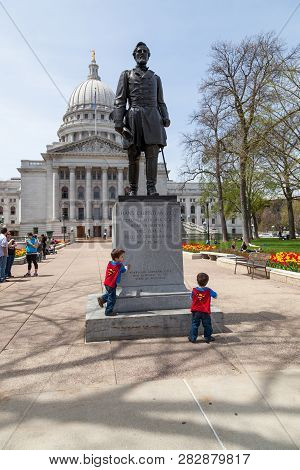 Madison, Wisconsin - May 10, 2014: Two Small Children In Superman Capes Play In Front Of A Statue Of